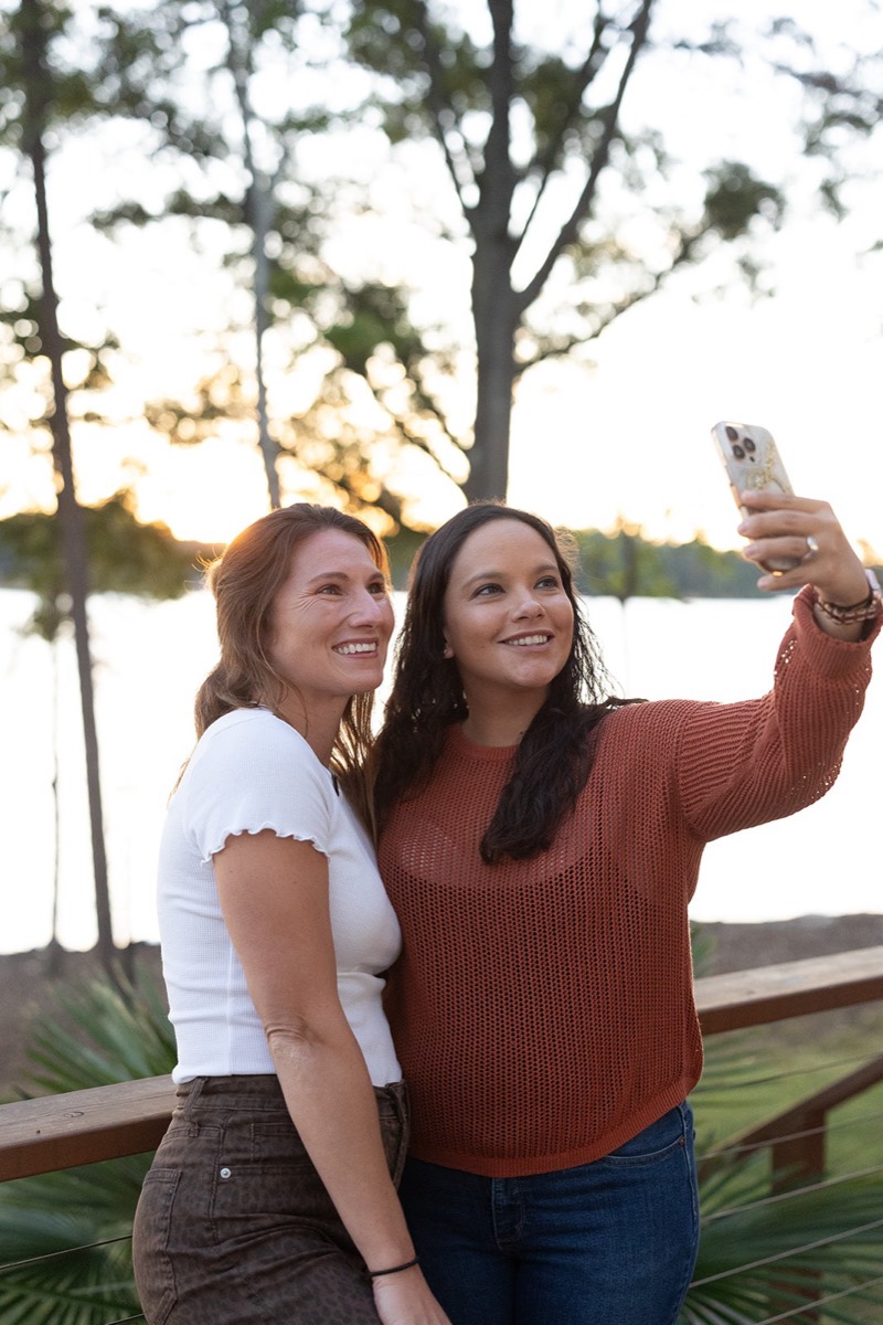 Friends taking a selfie at sunset by the lake